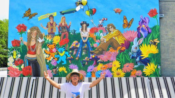 Chris Opp in front of Mural of people among flowers