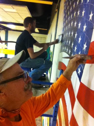 Chris Opp and a man painting a U.S.A. Banner on a wall