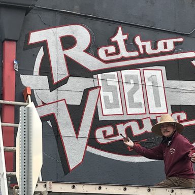 Chris Opp standing next to Mural of "Retro 521 Venue" on side of building